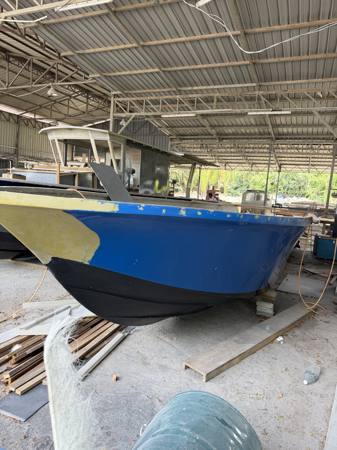 Blue working boat undergoing surface preparation and composite repair